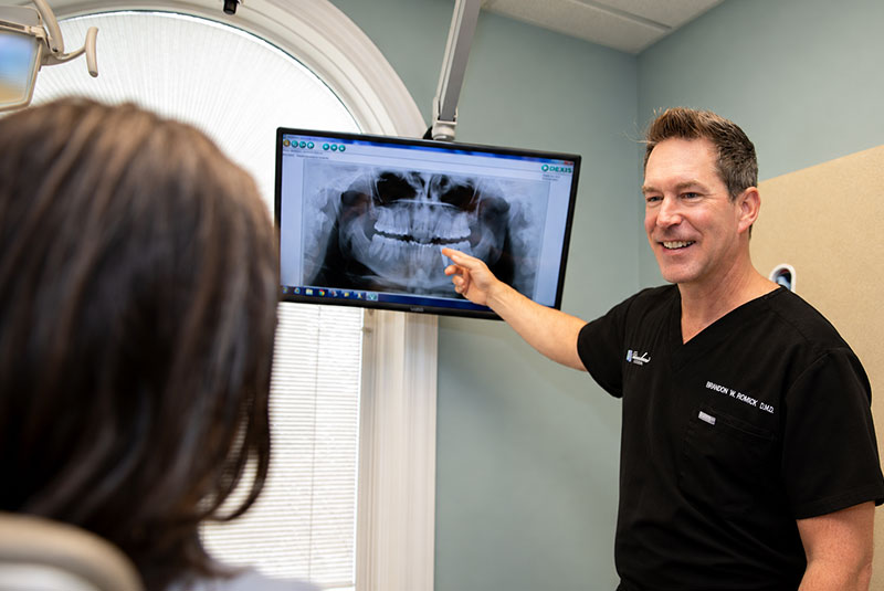 Dr. Brandon Romick explaining a panoramic dental X-ray to a patient during a consultation.